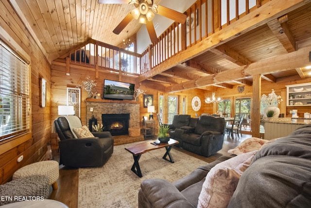 living room featuring wooden walls, wood finished floors, and ceiling fan with notable chandelier