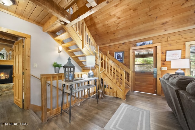 staircase featuring wood ceiling, a stone fireplace, wood walls, wood finished floors, and baseboards