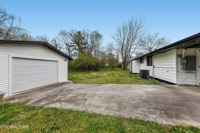 view of yard with central air condition unit, driveway, an outbuilding, and a garage