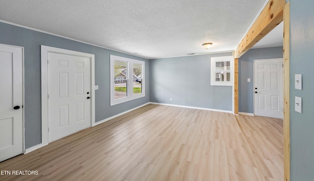 foyer featuring light wood-style flooring, a textured ceiling, and baseboards