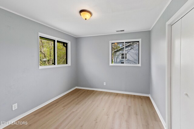 unfurnished room with visible vents, baseboards, wood finished floors, and ornamental molding