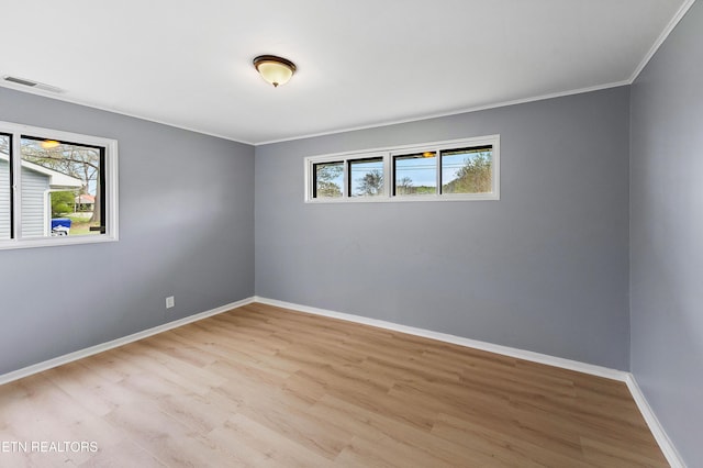 unfurnished room featuring light wood-style flooring, a wealth of natural light, and ornamental molding