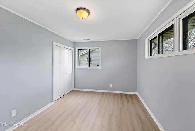 empty room with light wood-type flooring, baseboards, ornamental molding, and visible vents
