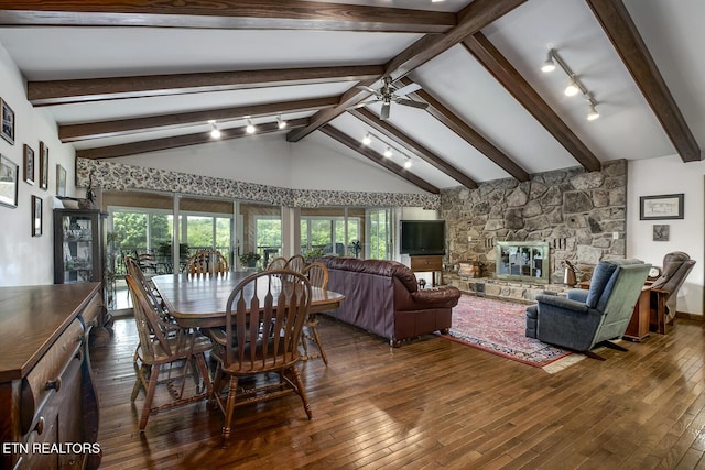 dining room featuring plenty of natural light, a ceiling fan, a stone fireplace, and hardwood / wood-style floors