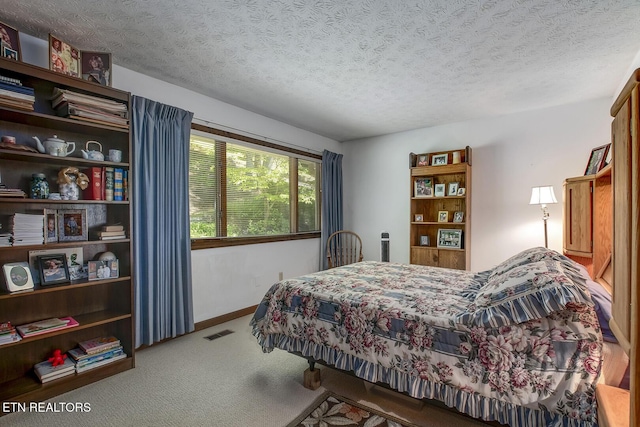 carpeted bedroom featuring baseboards, a textured ceiling, and visible vents