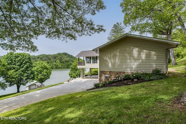 exterior space with a lawn, a water view, and driveway