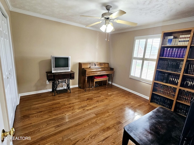 interior space featuring baseboards, ornamental molding, ceiling fan, and wood finished floors