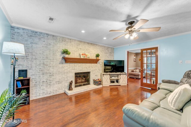 living area featuring crown molding, ceiling fan, a brick fireplace, and wood finished floors