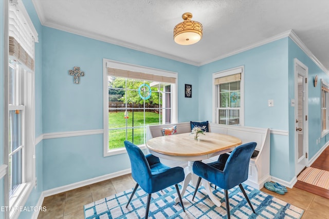 dining room with baseboards, tile patterned floors, crown molding, and a textured ceiling