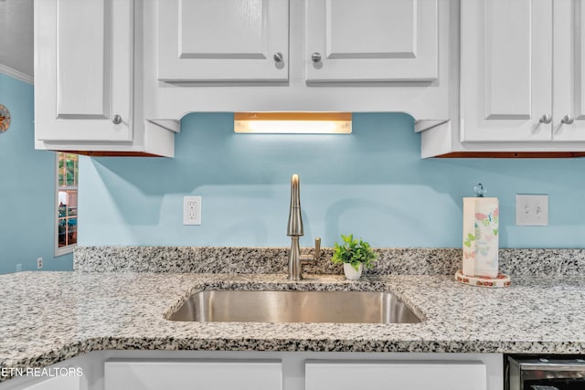 details featuring white cabinetry, light stone counters, and a sink