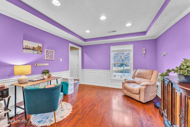 living area featuring a wainscoted wall, hardwood / wood-style floors, visible vents, recessed lighting, and a tray ceiling