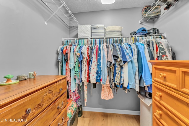 walk in closet with wood finished floors