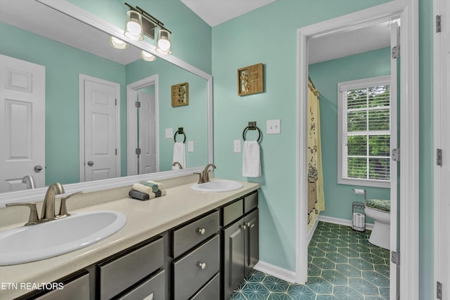 full bathroom with double vanity, tile patterned floors, baseboards, and a sink