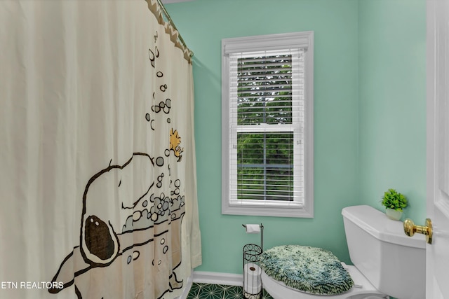 bathroom with toilet, baseboards, and plenty of natural light