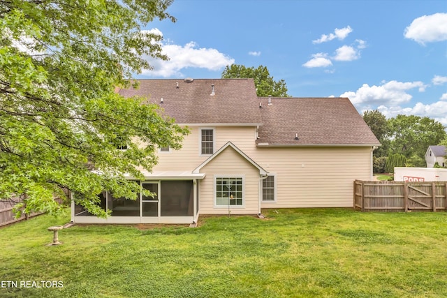 rear view of property with a yard, a sunroom, and fence