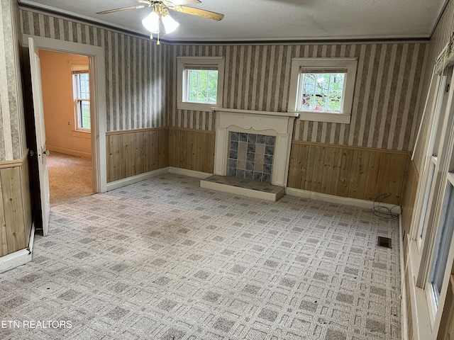 922 W Central Ave, Lafollette, TN 37766 - unfurnished living room featuring wallpapered walls, a tile fireplace, a wainscoted wall, baseboards, and ceiling fan