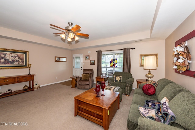 living room with a ceiling fan, baseboards, light colored carpet, and a tray ceiling