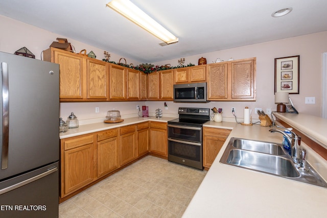 kitchen featuring appliances with stainless steel finishes, light countertops, and a sink