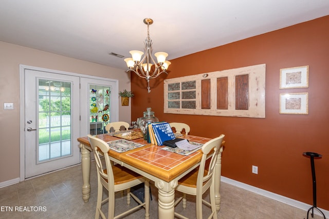 dining area with light tile patterned flooring, an inviting chandelier, visible vents, and baseboards