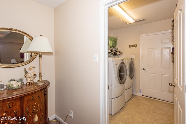 clothes washing area with washing machine and dryer, visible vents, laundry area, and baseboards