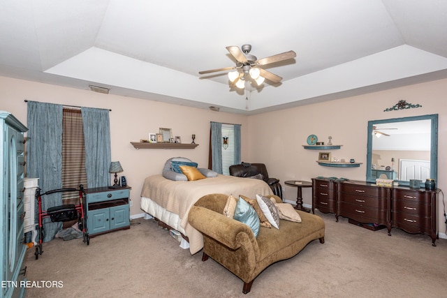 bedroom with vaulted ceiling, ceiling fan, carpet floors, and a tray ceiling