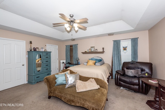 bedroom featuring light colored carpet, a raised ceiling, and visible vents