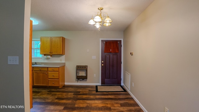 unfurnished dining area with an inviting chandelier, heating unit, dark wood-type flooring, visible vents, and baseboards