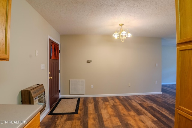 foyer featuring an inviting chandelier, a textured ceiling, visible vents, and dark wood finished floors