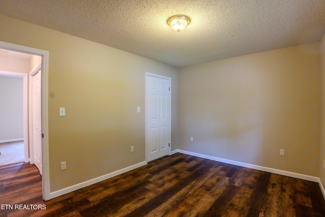 unfurnished room with dark wood finished floors, baseboards, and a textured ceiling