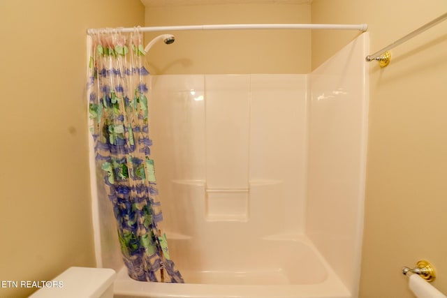bathroom featuring toilet and shower / bath combination with curtain