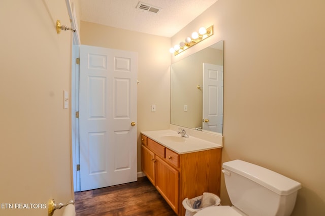 bathroom with visible vents, wood finished floors, toilet, and vanity