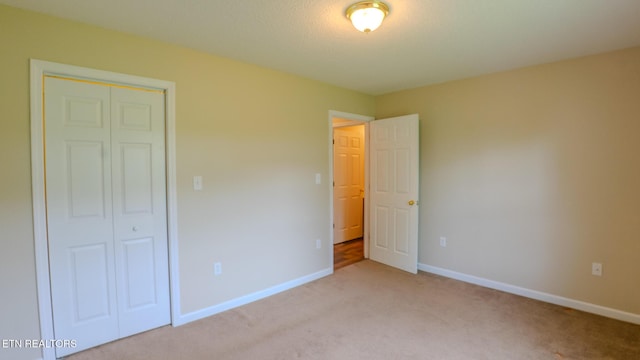 unfurnished bedroom featuring a closet, light carpet, and baseboards