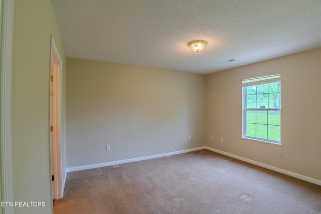 unfurnished room with a textured ceiling, visible vents, baseboards, and carpet floors