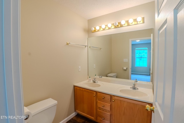 bathroom with toilet, double vanity, and a sink