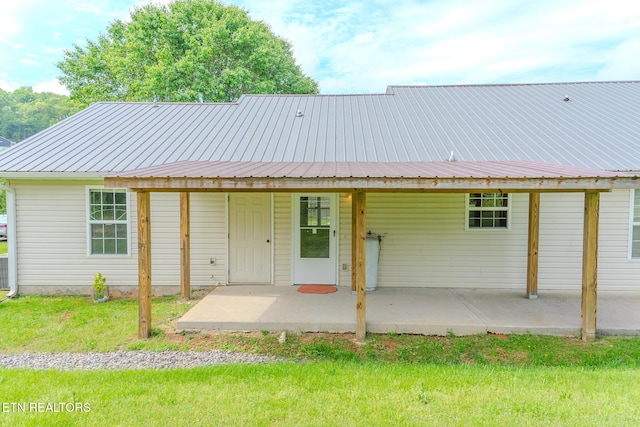 rear view of house featuring metal roof and a yard