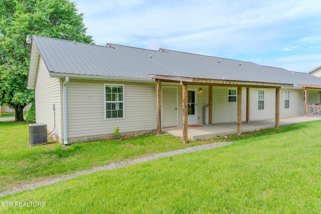 back of house featuring cooling unit, a patio, metal roof, and a lawn