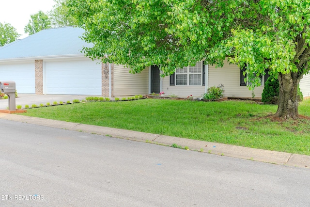 view of front of property featuring a front yard, driveway, an attached garage, and brick siding