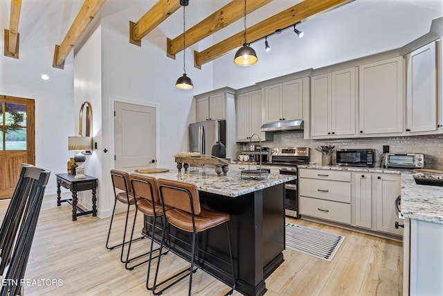 790 Pleasure Rd, Sevierville, TN 37876 - kitchen with decorative backsplash, under cabinet range hood, stainless steel appliances, and a breakfast bar area