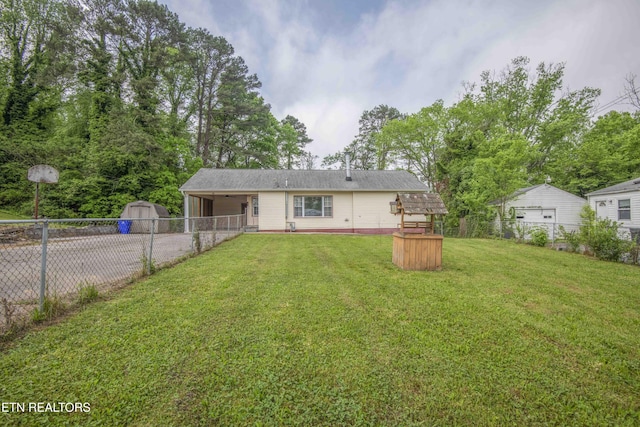 back of house with fence, a storage shed, a lawn, a carport, and driveway