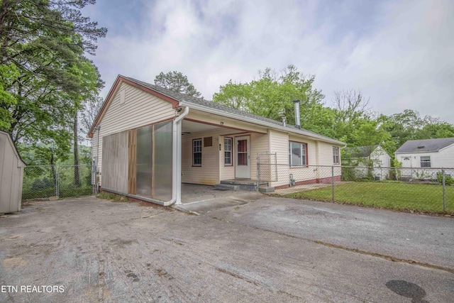 back of house featuring a lawn, aphalt driveway, fence, and an attached carport