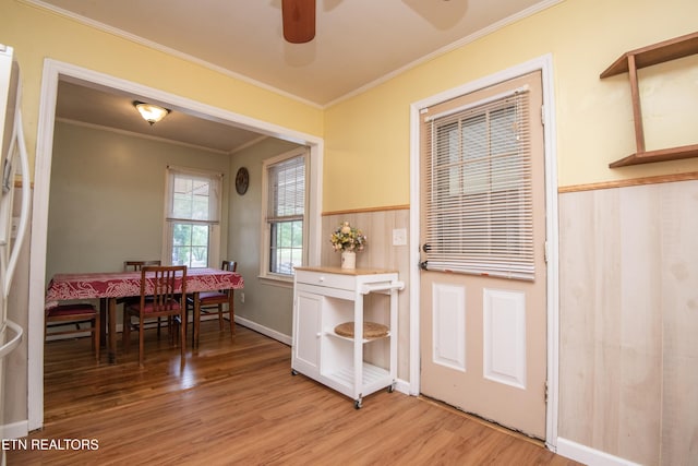 dining space with baseboards, ornamental molding, a ceiling fan, and light wood finished floors