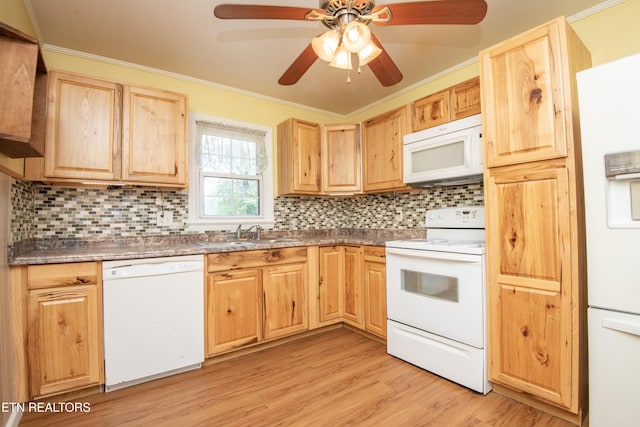 kitchen with light brown cabinets, white appliances, tasteful backsplash, a sink, and light wood finished floors