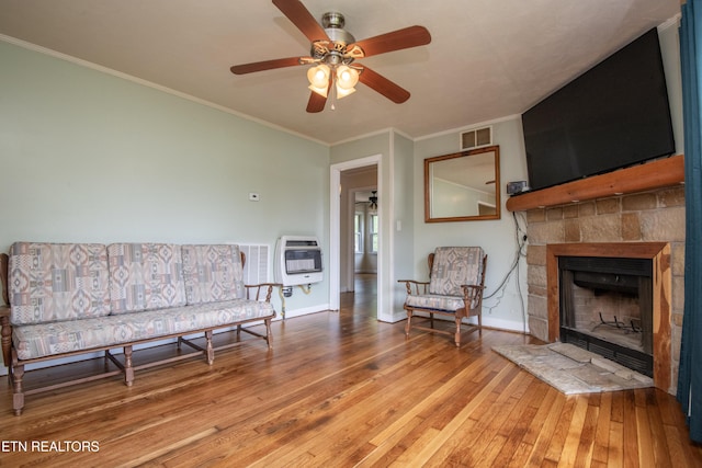 living area featuring heating unit, baseboards, hardwood / wood-style flooring, and visible vents