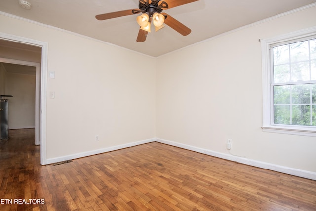empty room featuring crown molding, baseboards, and hardwood / wood-style flooring