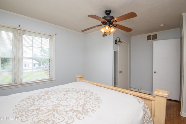bedroom with ceiling fan, visible vents, ornamental molding, and wood finished floors