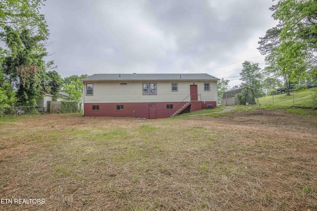 rear view of house with fence, a lawn, and crawl space