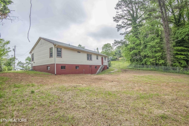 back of house featuring a lawn and fence