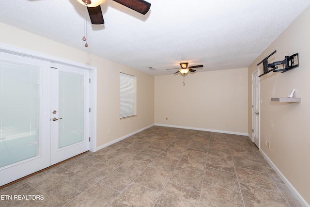 empty room featuring baseboards, ceiling fan, a textured ceiling, french doors, and stone finish flooring
