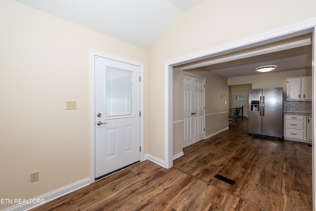 foyer entrance with baseboards, dark wood-style flooring, and vaulted ceiling