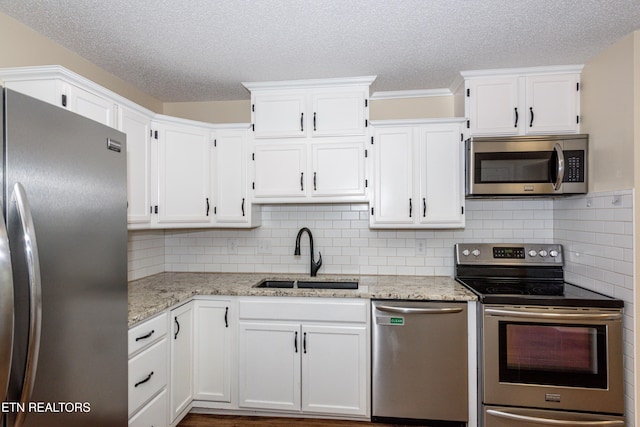 kitchen with a sink, a textured ceiling, appliances with stainless steel finishes, and white cabinets